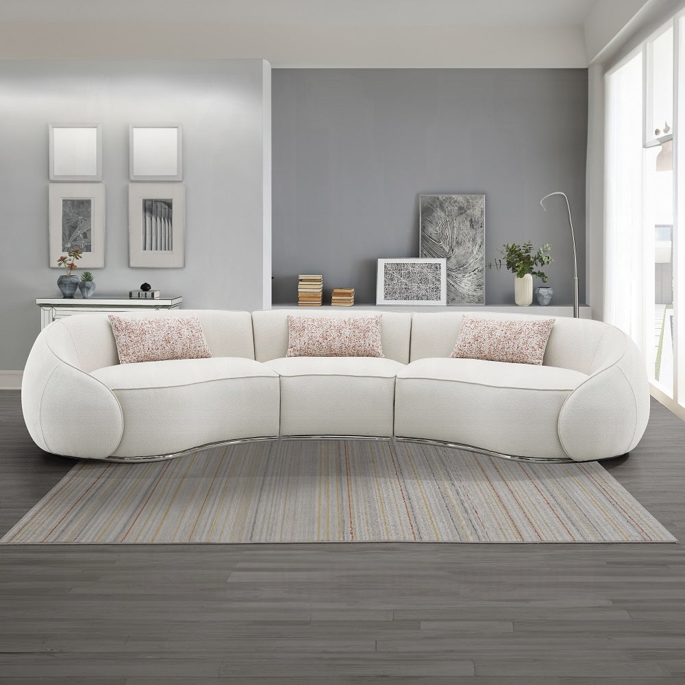 Modern living room with a white curved sofa, decorative pillows, and wall art.