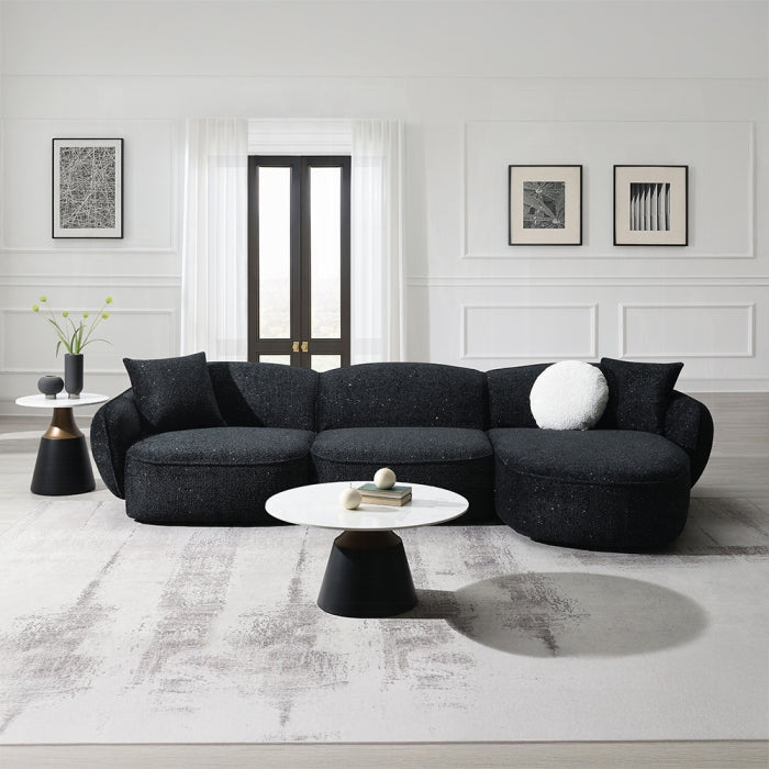 Modern living room with a black sectional sofa, white coffee table, and minimal decor.