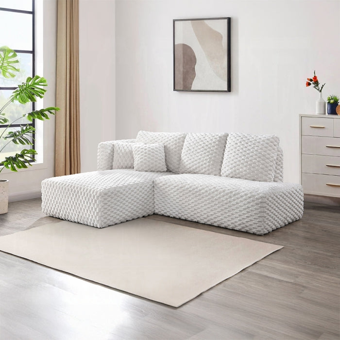 White textured sectional sofa in a room with a rug, plant, and dresser.
