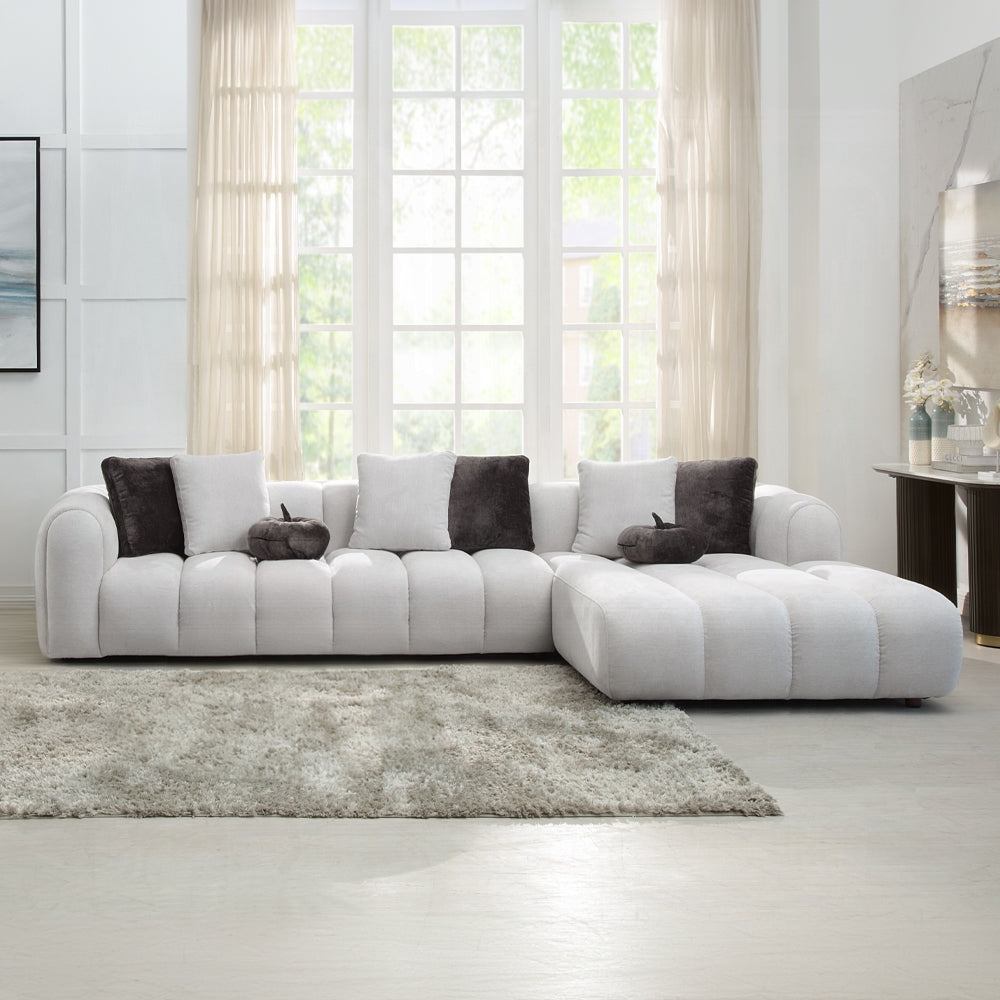 White sectional sofa with colored grey cushions in a bright living room.