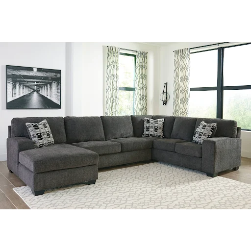Gray sectional sofa in a living room with a rug and window.