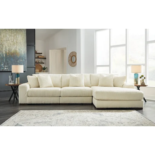 Beige sectional sofa in a living room setting with large windows and decor.